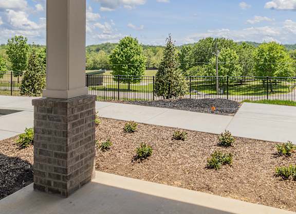 A view from a covered porch looking out to a landscaped yard.