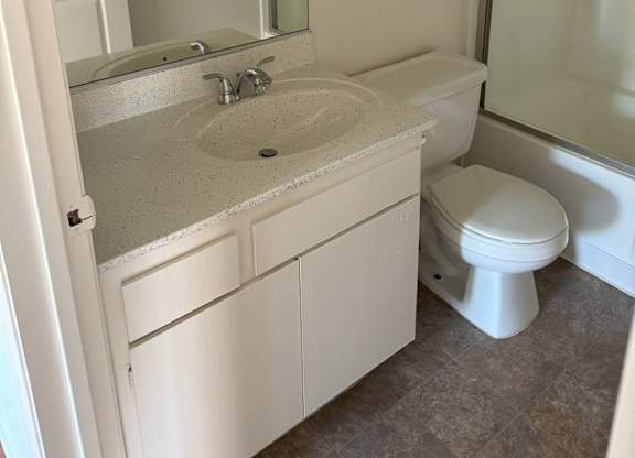 A white bathroom with a sink, toilet and shower.