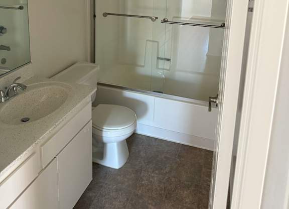A white bathroom with a toilet, sink, and shower.