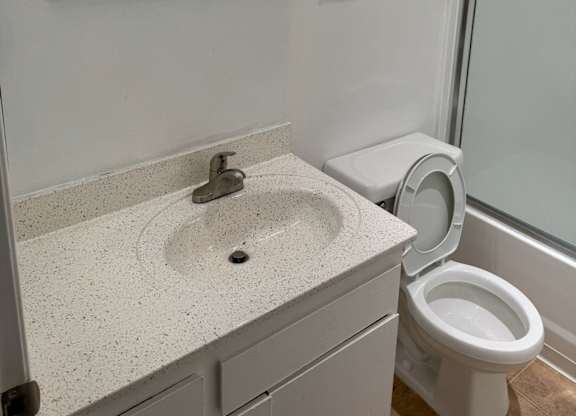 A white bathroom with a sink, toilet, and mirror.