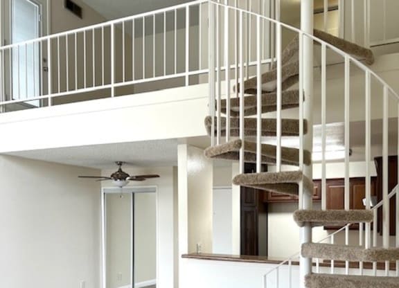 A spiral staircase with a carpeted runner leads up to a second floor.