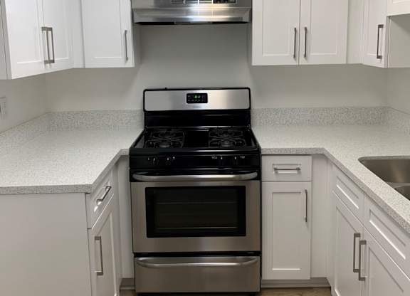 A kitchen with white cabinets and a stainless steel oven.