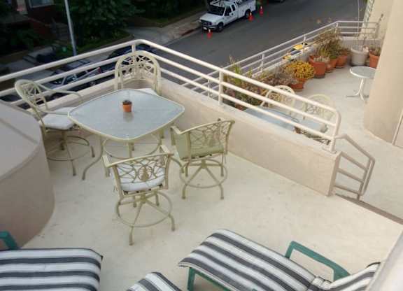 A patio with a table and chairs overlooking a street.