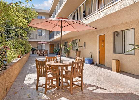 A patio with a table and chairs under an umbrella.