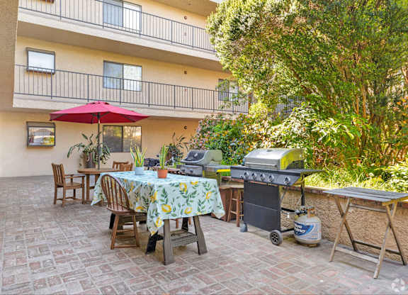 A patio with a table set for dining and a grill.