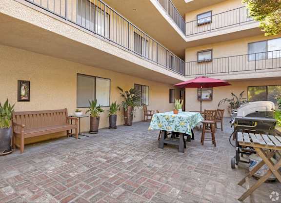 A patio with a table and chairs and a bench.