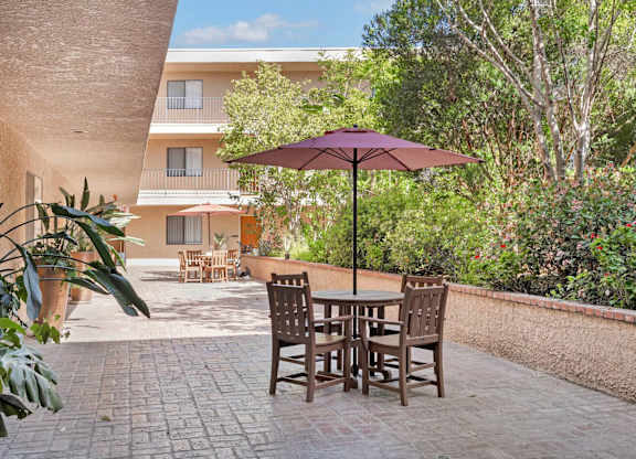 A patio with a table and chairs and an umbrella.