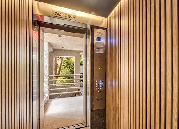 A modern elevator with a wooden panel design and a digital display above the control panel.