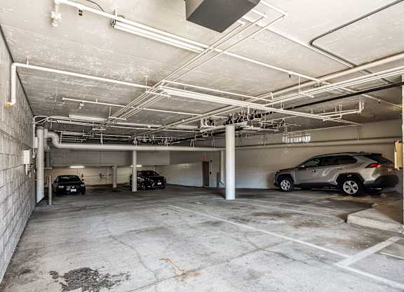 A parking garage with a few cars parked in it.