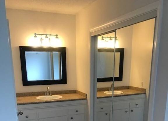 A bathroom with a sink, mirror, and cabinets.