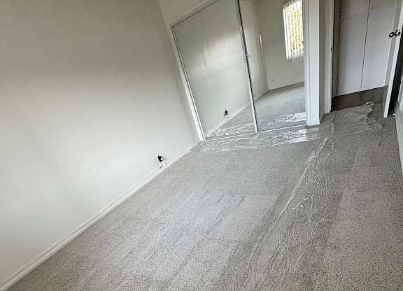 A room with a carpeted floor and a door on the right side.