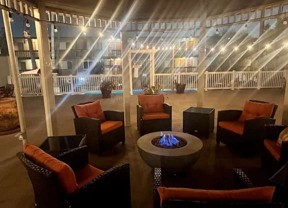 A patio with a table and chairs and a fire pit.