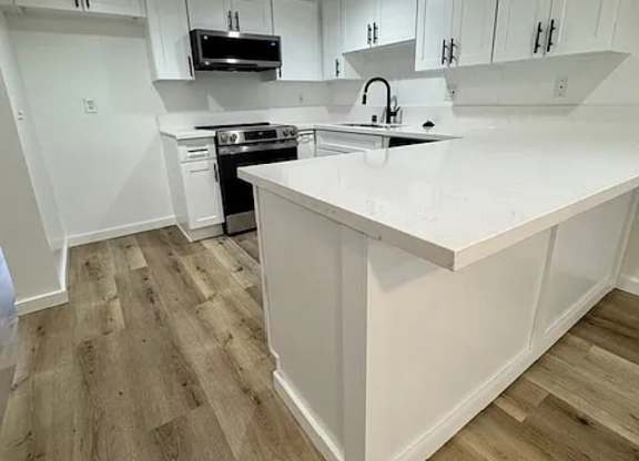 A kitchen with white cabinets and a white island.