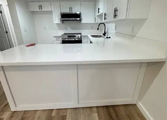 A kitchen with white cabinets and a wooden floor.