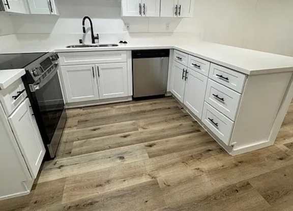 A kitchen with white cabinets and a wooden floor.