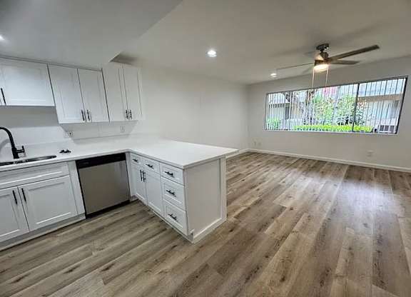 A kitchen with white cabinets and a wooden floor.