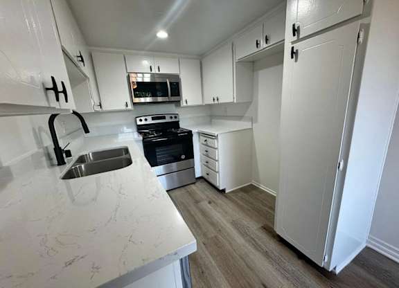 A kitchen with white cabinets and a marble countertop.
