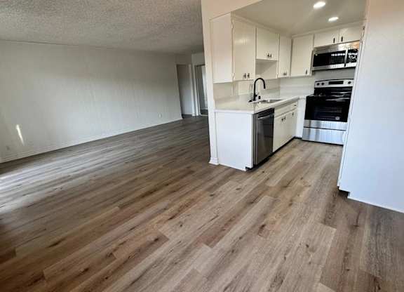 A kitchen with a white countertop and wooden flooring.