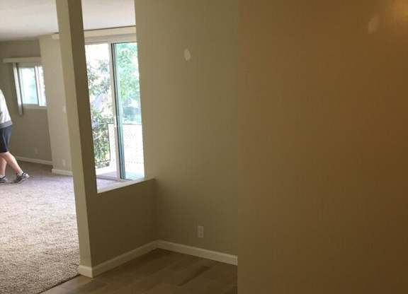 A room with wooden flooring and a person standing by a door.