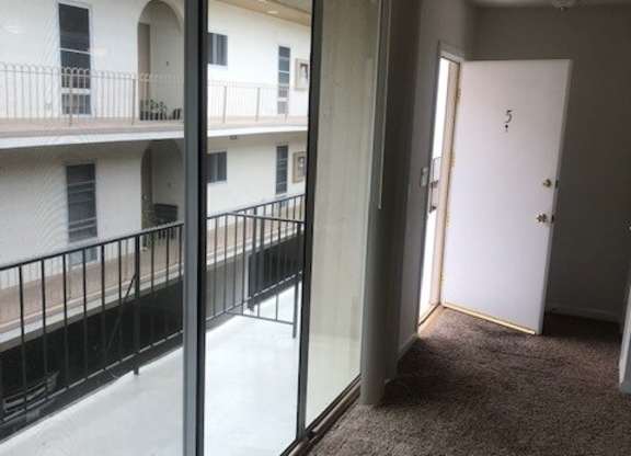 A view of a balcony from a room with a door.