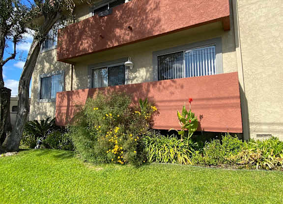 A building with a red awning and a green lawn in front.