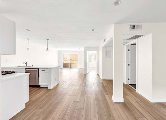 A kitchen with white cabinets and a wooden floor.