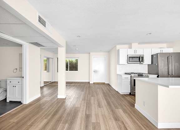 A kitchen with white cabinets and a wooden floor.