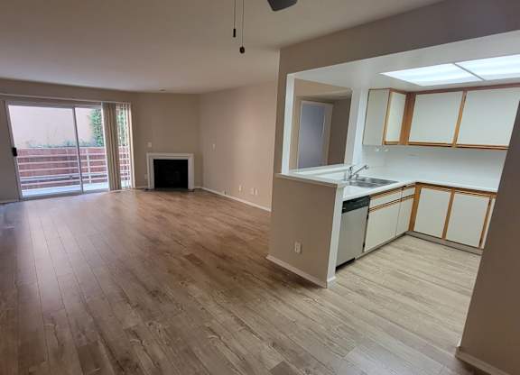 A kitchen area with a sink, cabinets, and a window.