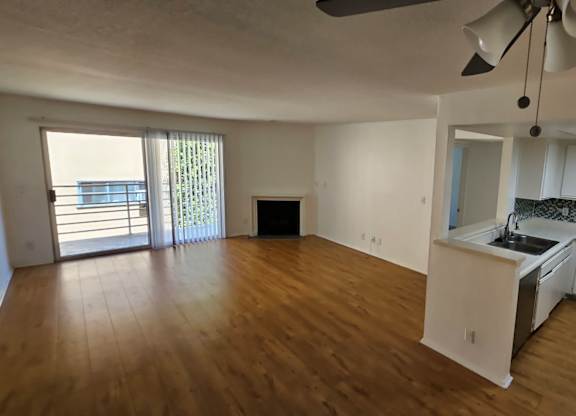 A room with a ceiling fan and wooden flooring.