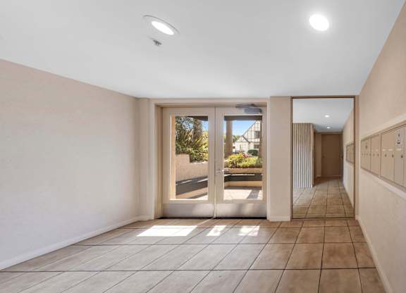 A hallway with a tiled floor and a large mirror on the wall.