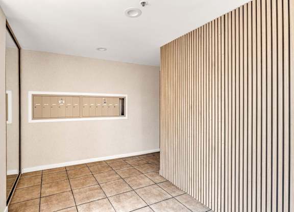 A room with a wooden panel on the wall with mailboxes.