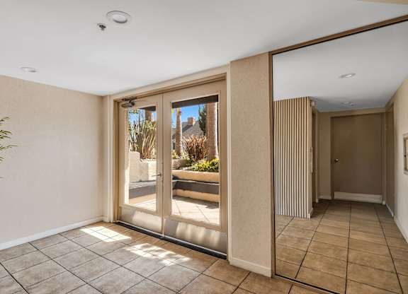 A room with a glass door leading to entrance of the apartment building.