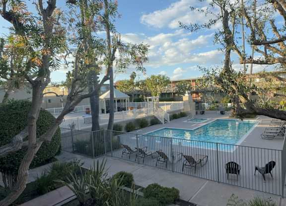A pool surrounded by trees and chairs.