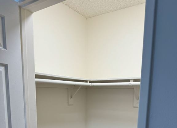 A white closet with a white door and a white shelf.