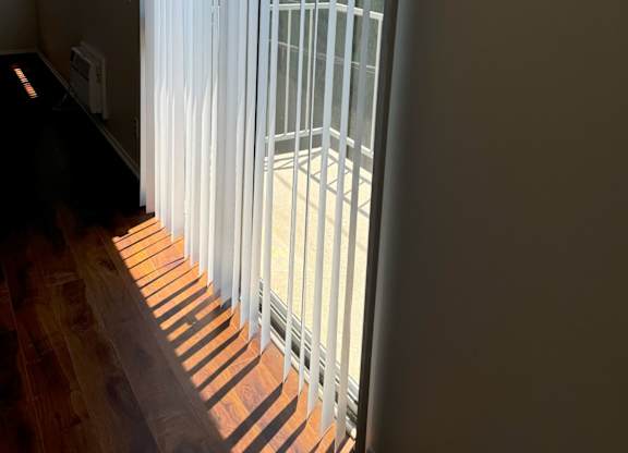 A window with white blinds is open, letting in sunlight.