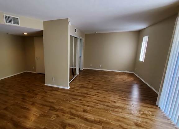 A room with wooden flooring and a window on the right side.