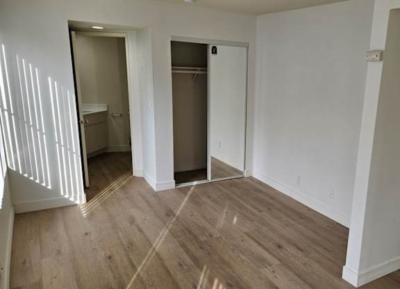 A room with wooden floors and white walls with two doors.
