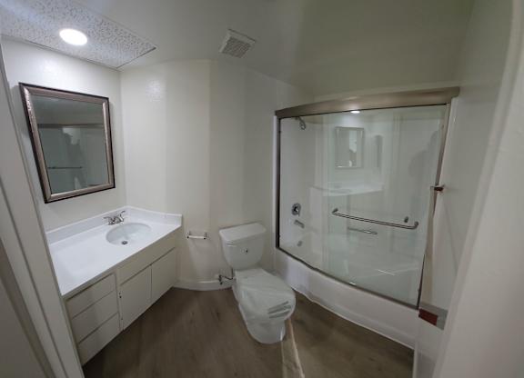 A white bathroom with a toilet, sink, and shower.