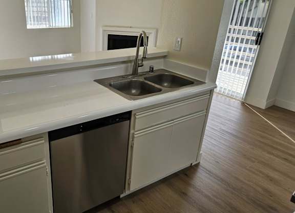 A kitchen with a white counter top and a stainless steel dishwasher.