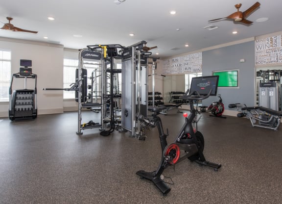 a spacious fitness room with cardio equipment and a large screen tv at The Whitworth, Williamsburg, Virginia