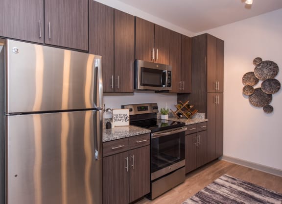 a kitchen with dark wood cabinets and stainless steel appliances at The Whitworth, Virginia, 23185