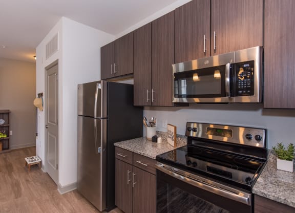 a kitchen with dark wood cabinets and stainless steel appliances at The Whitworth, Williamsburg, VA