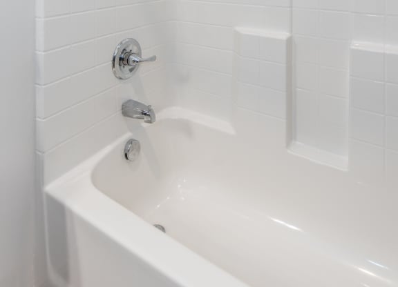 a bathroom with white tile and a white bathtub at The Whitworth, Virginia, 23185