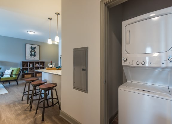 a kitchen with a washer and dryer and a bar with stools at The Whitworth, Williamsburg, VA