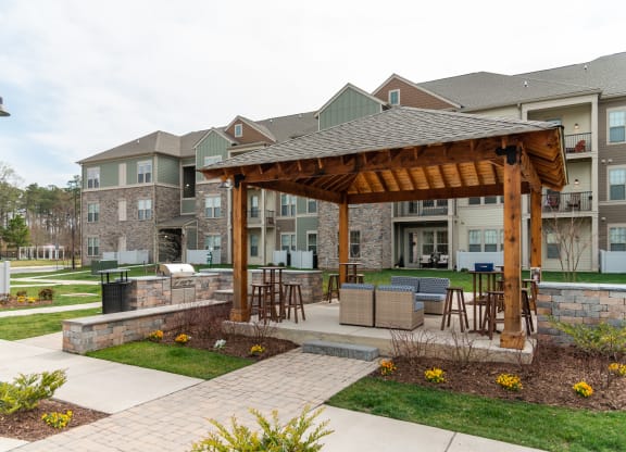 a large wooden pavilion with a stone wall in front of an apartment complex at The Whitworth, Williamsburg, VA