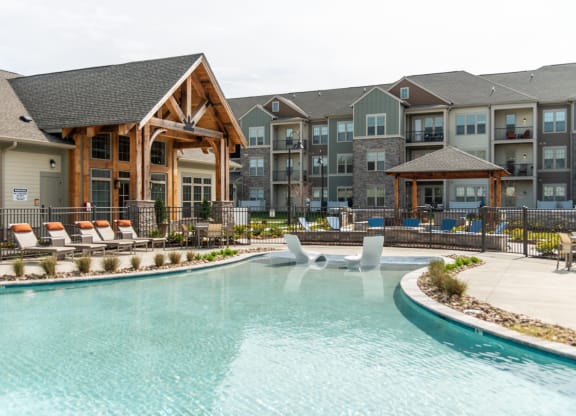 a swimming pool with lounge chairs and a lazy river in front of an apartment building at The Whitworth, Virginia