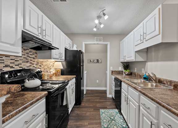 A kitchen with black appliances and white cabinets.