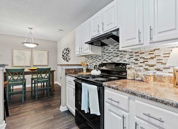 A kitchen with a black stove top oven and white cabinets.