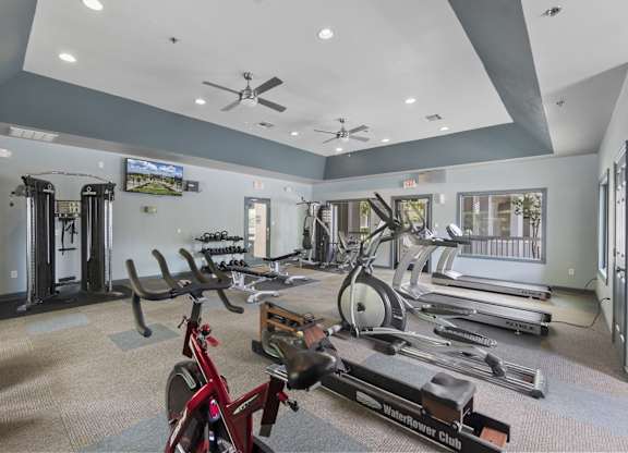A gym with a variety of equipment including treadmills, stationary bikes, and weight machines.