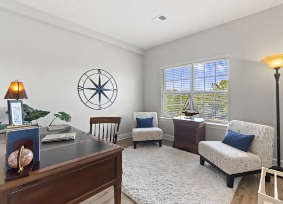 A room with a compass on the wall and a lamp on the desk.